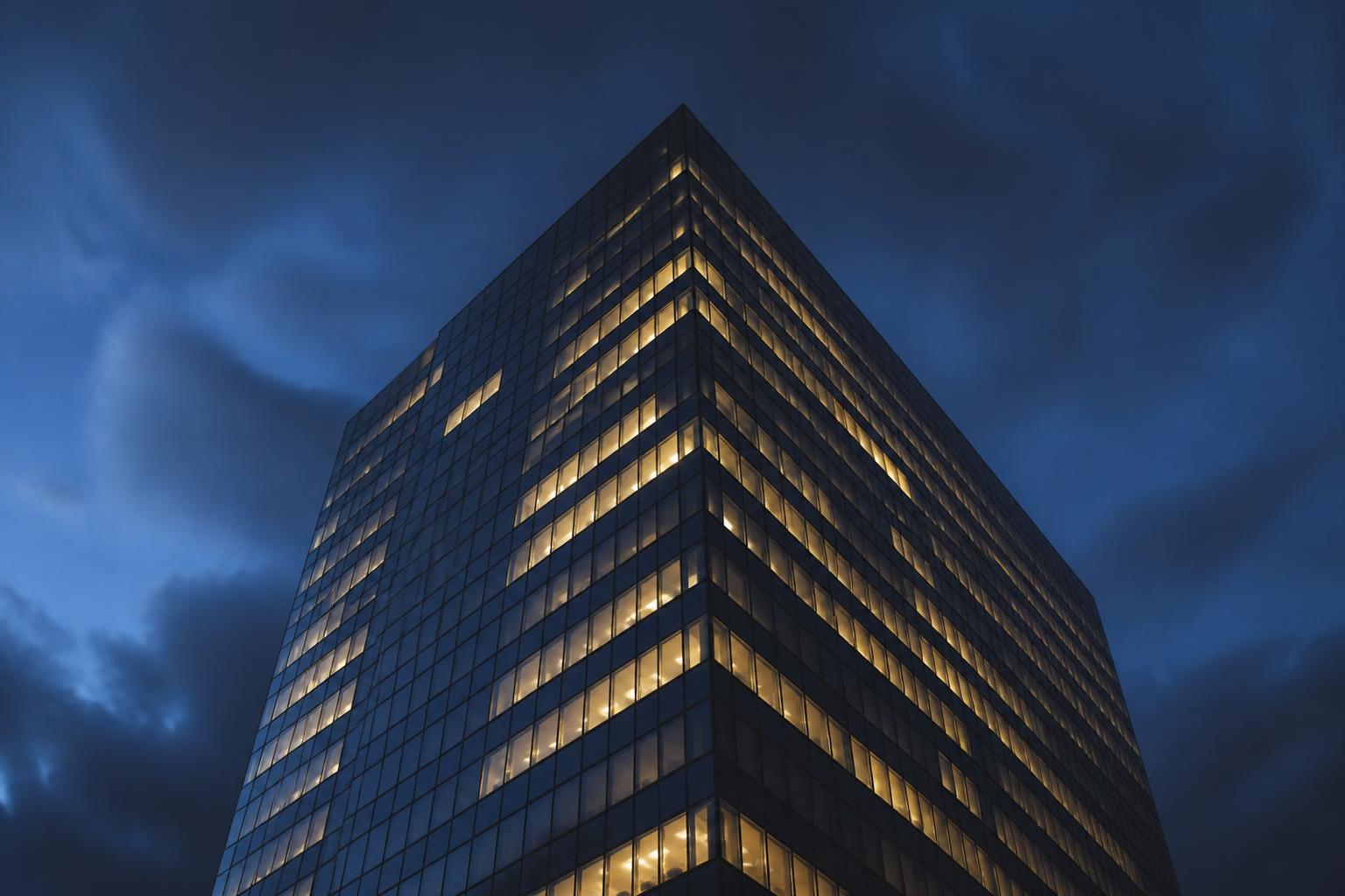 Modern corporate office tower at twilight with warmly lit windows